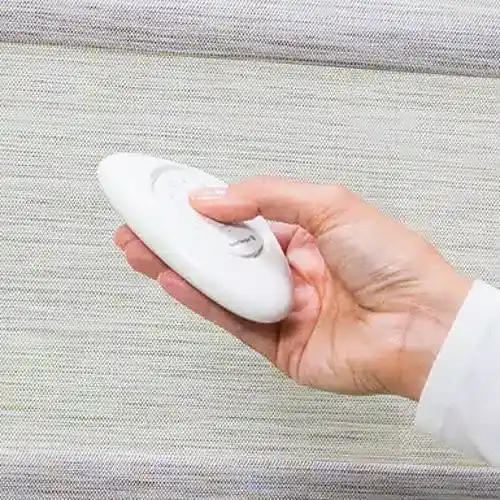 Hand holding a portable garment steamer against a neutral background for quick home ironing.