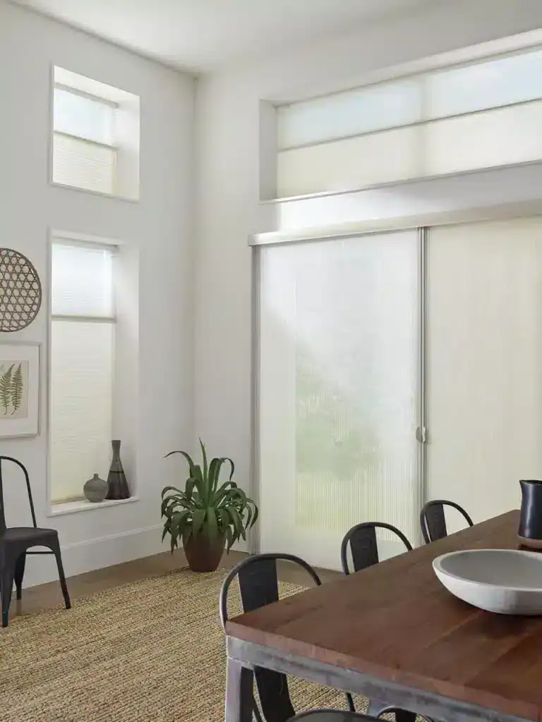 Sunlit dining space with large windows, natural light, contemporary decor, and wooden furniture for a cozy, stylish ambiance.