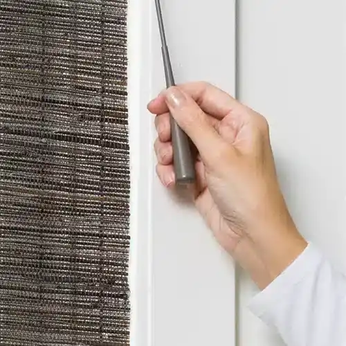 Close-up of person repairing or installing a screen door or window with a screwdriver.