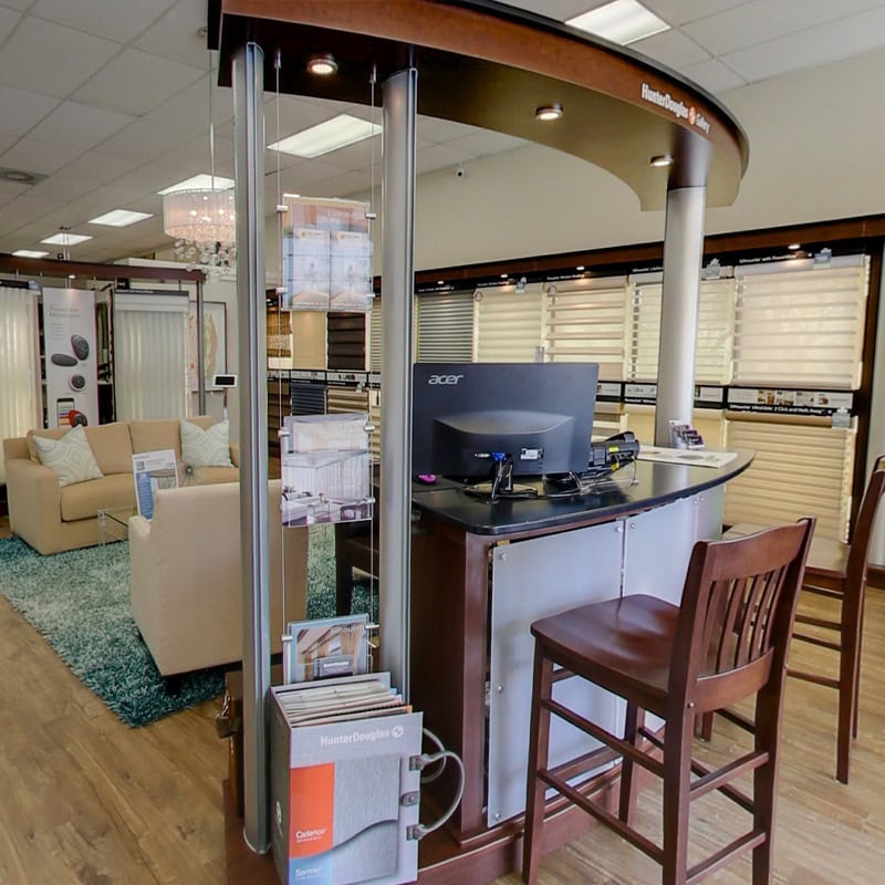 Customer service desk with computer and chairs in a furniture store showroom.
