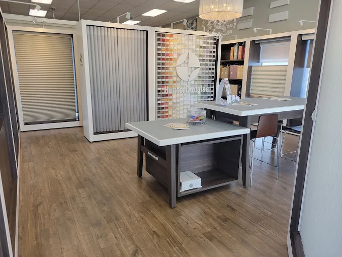 Showroom interior displaying various window blinds and shades with a desk and sample displays.