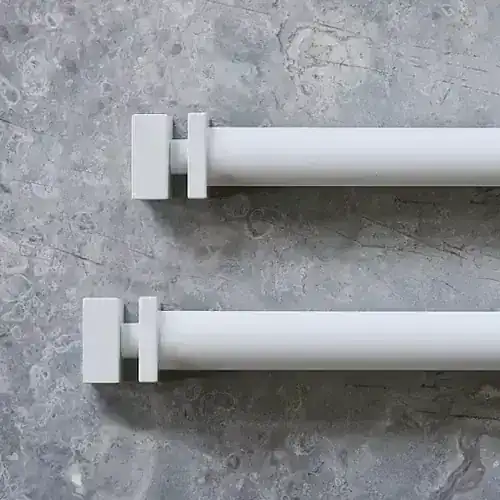 Two white curtain rods with brackets on a textured gray surface, ready for installation or use in home decor.