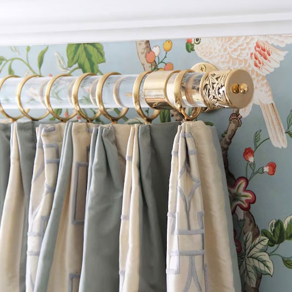 Close-up of gold and brass curtain rod with decorative finial and hanging curtains in a stylish room.