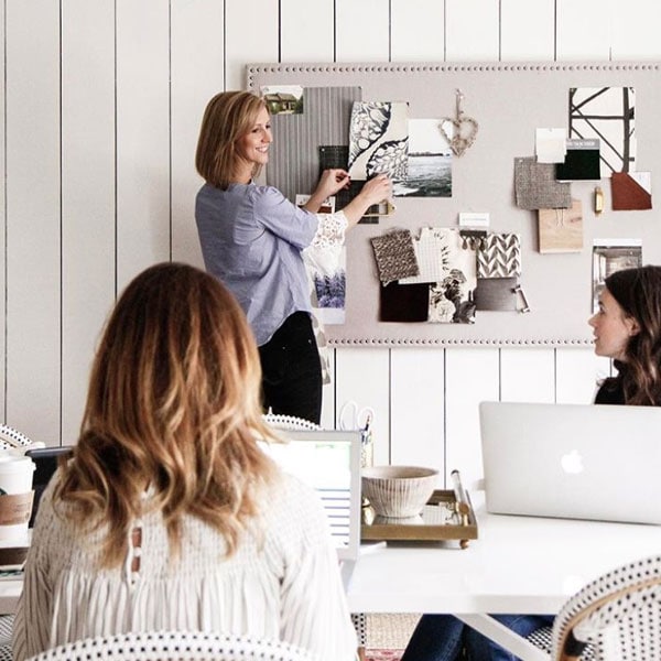 Interior design professional presenting fabric and material samples to clients in a modern office setting.