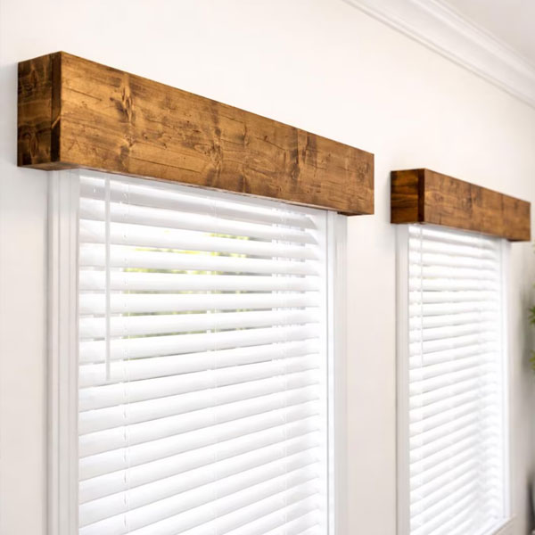 Close-up of wooden window valances with white blinds in a modern interior setting.