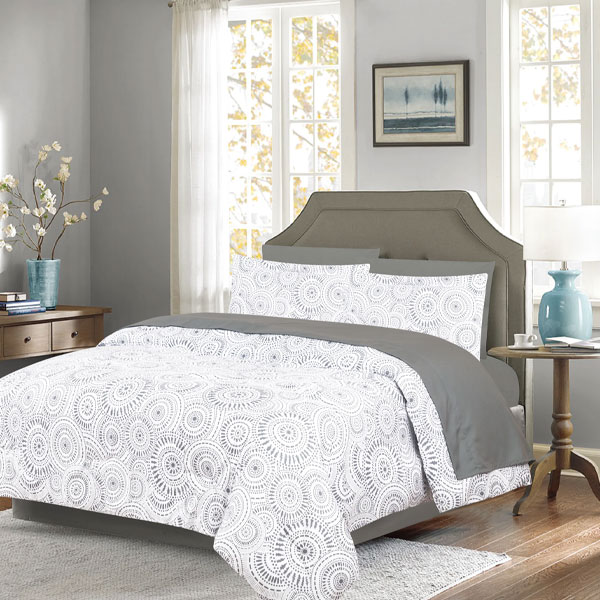 Cozy bedroom featuring a large bed with white and gray bedding, a beige headboard, and natural light from large windows.
